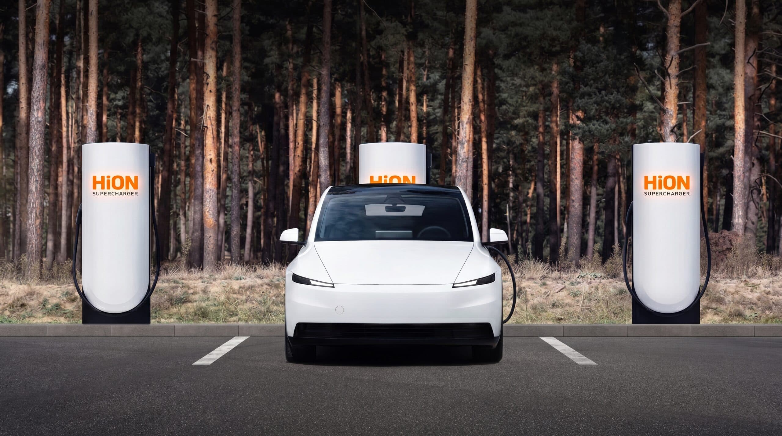 A white EV parked between HiON Supercharger pillars on a forest pull-off, each matte-white face marked with the glowing orange HiON wordmark.
